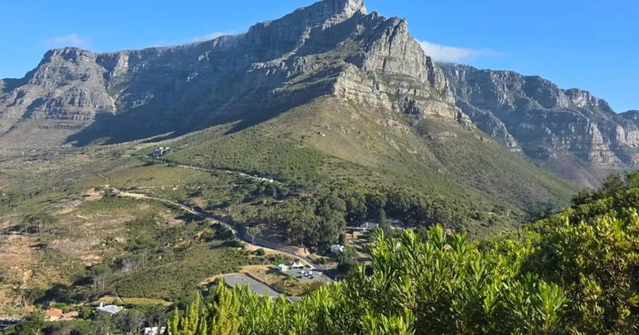 The front of Table Mountain and its ridges above green lower slopes under a blue sky